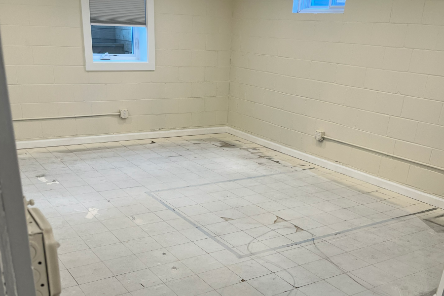 Empty room with white walls and floor, showing worn marks and two windows.