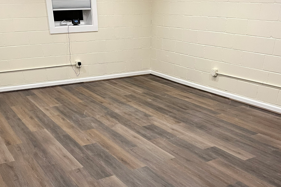 Empty room with wood-patterned vinyl flooring and white walls.