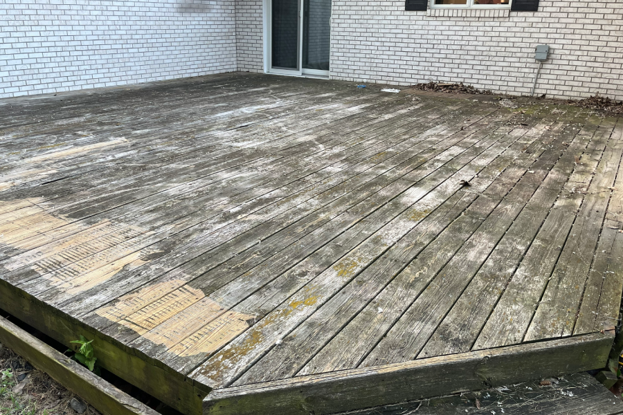 Weathered wooden deck with peeling paint and moss growth.