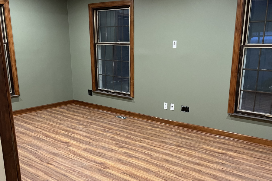 Empty room with wood flooring and green walls.